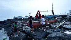 epa12404688 Children walk next to fishing boats placed on high ground in anticipation of an approaching typhoon in Cavite City, Philippines, 25 September 2025. The Philippine weather bureau advised the public to remain vigilant for possible flash floods and landslides brought by Typhoon Bualoi. EPA/FRANCIS R. MALASIG