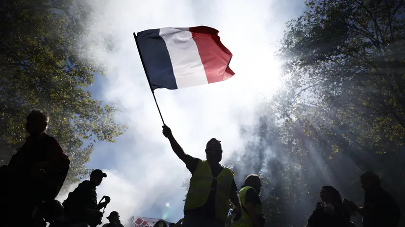 epa12387107 A man waves a French flag during a demonstration against austerity measures in the upcoming budget in Paris, France, 18 September 2025. French unions have called for a nationwide strike and mass protests against the planned cuts in the government’s draft budget for 2026. EPA/YOAN VALAT