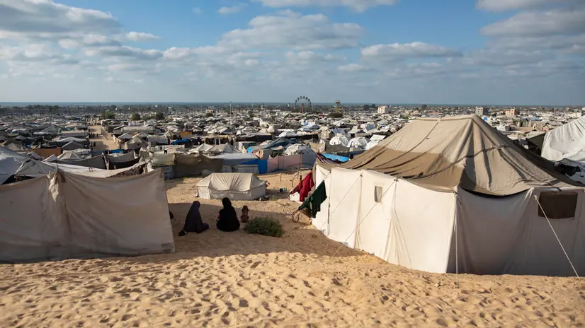epa12415098 Displaced Palestinians from the northern Gaza Strip sit next to their tents in the Al-Mawasi area of Khan Younis, in the southern Gaza Strip, 25 September 2025. According to the UN, around 90 per cent of the population or 1.9 million people in Gaza, have been displaced since the start of the conflict. EPA/HAITHAM IMAD