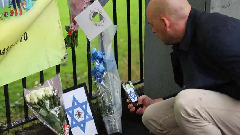 epa12427117 A person photographs flowers and tributes left at the scene of a deadly terror attack in Manchester, Britain, 03 October 2025. Two people died after a car and stabbing attack at a synagogue in Manchester on 02 October, and the attacker, who has been named as 35-year-old British citizen Jihad Al-Shamie, was shot dead by police. EPA/ADAM VAUGHAN