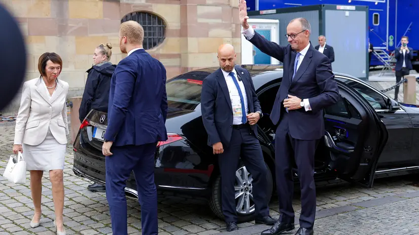 epa12426955 German Chancellor Friedrich Merz waves as he arrives (R) at an ecumenical service as part of celebrations for the Day of German Unity, in Saarbruecken, Germany, 03 October 2025. German Unity Day is marked annually on 03 October to commemorate the reunification of East and West Germany in 1990. EPA/CHRISTOPHER NEUNDORF