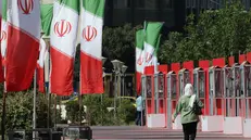 epa12285709 A person walks by a row of Iranian flags on a street in Tehran, Iran, 06 August 2025. Tension between Iran and world powers continues. EPA/ABEDIN TAHERKENAREH