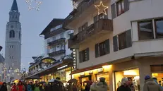 Turisti mentre passeggiano sotto la pioggia lungo Corso Italia a Cortina d'Ampezzo (Belluno), in una immagine del 08 dicembre 2010. La neve per ora resta la grande assente del primo fine settimana di dicembre a Cortina. Nel capoluogo dolomitico a farla da padrone, da stamane, e' la pioggia. Per i patiti degli sport invernali non resta che affrontare le piste in quota. Si scia ormai da una settimana sul monte Faloria, con l'apertura della funivia, che sale dal centro del paese, e della seggiovia quadriposto Vitelli, sino alla sommita' dei Tondi, a 2.200 metri. Da oggi al via anche l'area sciistica delle Cinque Torri, con la seggiovia quadriposto che porta al rifugio Scoiattoli. ANSA/ANDREA SOLERO