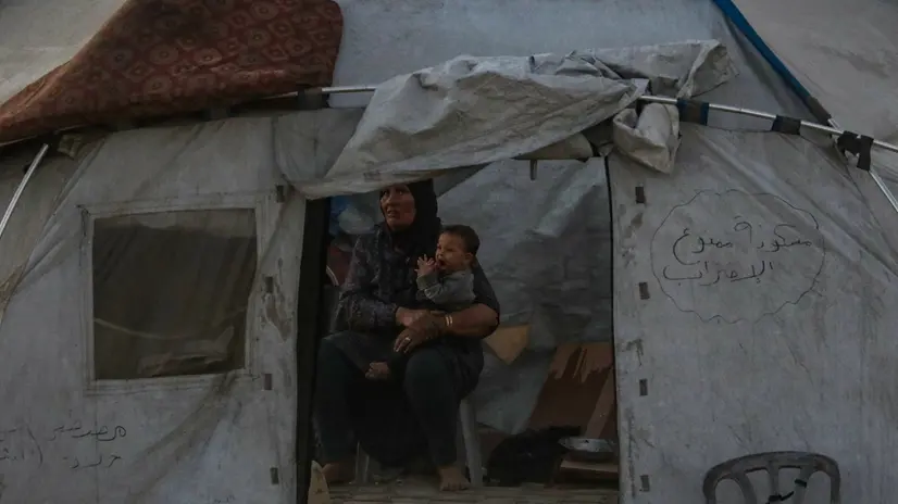 epaselect epa12438128 An internally displaced Palestinian mother carrying her child in their tent at the Gaza port during an Israeli military operation in Gaza City, Gaza Strip, 07 October 2025. According to the UN around 90 percent of the population or 1.9 million people in Gaza have been displaced since the start of the conflict. More than 67,000 Palestinians have been killed in the Gaza Strip since October 2023, according to the Palestinian Ministry of Health, and about 1,200 Israelis have been killed since the launch of an Israeli military campaign in response to a cross-border attack by Hamas on 07 October 2023. EPA/MOHAMMED SABER