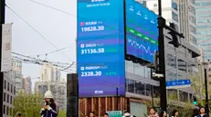 epa12015255 People walk on a street near screens showing stock exchange and economic data in Shanghai, China, 07 April 2025. Hong Kong and Chinese stocks plummeted dramatically on April 7 after Beijing countered US tariffs with its own set of trade levies. The move sent shock waves through financial markets, igniting fears among investors of an expanding trade war that could plunge the global economy into a severe recession. EPA/ALEX PLAVEVSKI