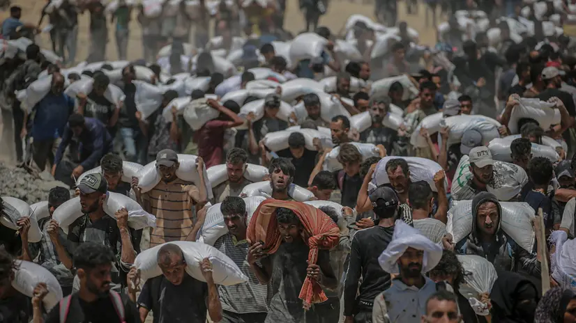 epa12434333 (FILE) - Internally displaced Palestinians carry bags of flour near a food distribution point in Zikim, northern Gaza Strip, 27 July 2025 (reissued 06 October 2025). 07 October 2025 marks two years since the Palestinian militant group Hamas launched a surprise attack on Israel, taking dozens of hostages and killing nearly 1,200 people. In response, Israel began its war on Gaza, which has killed more than 66,000 people, displaced millions and destroyed the Palestinians enclave. EPA/MOHAMMED SABER