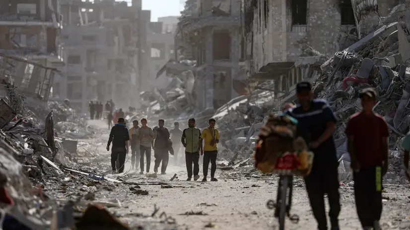 epa12447018 Palestinians walk along a street among the rubble of destroyed buildings amid a ceasefire between Israel and Hamas, in Gaza City, 11 October 2025. US President Donald Trump announced that Israel and Hamas have agreed to the first phase of a Gaza peace plan. The deal involves the release of Israeli hostages and Palestinian prisoners, the withdrawal of Israeli forces, and the delivery of humanitarian aid to Gaza. EPA/MOHAMMED SABER
