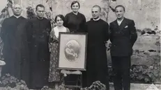 Maria, con i figli, posa con la foto del marito defunto - © www.giornaledibrescia.it