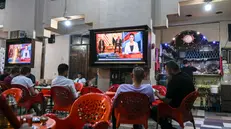 epa12451455 People watch the news broadcast during the Gaza Peace Summit in Sharm El-Sheikh, Egypt, 13 October 2025. US President Donald Trump alongside Egypt's President Abdel Fattah al-Sisi with leaders from more than 20 countries attend the summit in Sharm El-Sheikh. The first phase of Gaza peace plan between Israel and Hamas involves the release of Israeli hostages and Palestinian prisoners, the partial withdrawal of Israeli forces, and the delivery of humanitarian aid to Gaza. EPA/MOHAMED HOSSAM