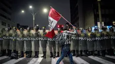 epa12457061 A person holds a Peruvian flag in front of members of the Peruvian police during a protest in Lima, Peru, 15 October 2025. Young people and labor union members protested across Peru against the government of Peruvian President Jose Jeri and Parliament, amid a wave of crime and insecurity in the country. EPA/JOHN REYES MEJIA