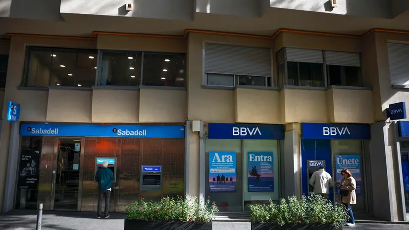 epa12444656 Customers use ATM machines at two adjacent Banco Sabadell and BBVA bank branches in Barcelona, Spain, 10 October 2025. Shareholders of Banco Sabadell have a deadline until midnight to decide wether to accept or not the exchange of shares proposed by BBVA in their takeover bid over Sabadell. EPA/Alberto Estevez