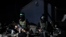epa12456503 Palestinian fighters from Hamas's Izz ad-Din al-Qassam Brigades guards as vehicles of the International Committee of the Red Cross (ICRC) arrive to transport remains of Israeli hostages handed over by Hamas in Gaza City, 15 October 2025. The first phase of the Gaza peace agreement, reached between Israel and Hamas, includes the release of Israeli hostages and Palestinian prisoners, a partial withdrawal of Israeli forces, and the delivery of humanitarian aid to Gaza. EPA/MOHAMMED SABER