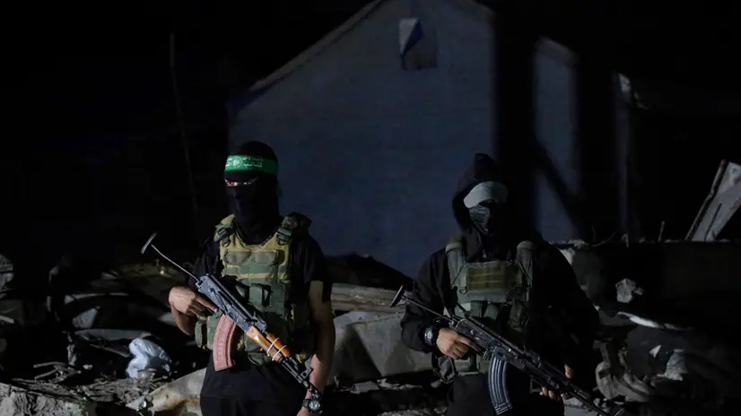 epa12456503 Palestinian fighters from Hamas's Izz ad-Din al-Qassam Brigades guards as vehicles of the International Committee of the Red Cross (ICRC) arrive to transport remains of Israeli hostages handed over by Hamas in Gaza City, 15 October 2025. The first phase of the Gaza peace agreement, reached between Israel and Hamas, includes the release of Israeli hostages and Palestinian prisoners, a partial withdrawal of Israeli forces, and the delivery of humanitarian aid to Gaza. EPA/MOHAMMED SABER