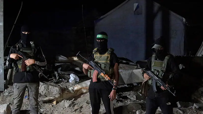 epa12456504 Palestinian fighters from Hamas's Izz ad-Din al-Qassam Brigades guards as vehicles of the International Committee of the Red Cross (ICRC) arrive to transport remains of Israeli hostages handed over by Hamas in Gaza City, 15 October 2025. The first phase of the Gaza peace agreement, reached between Israel and Hamas, includes the release of Israeli hostages and Palestinian prisoners, a partial withdrawal of Israeli forces, and the delivery of humanitarian aid to Gaza. EPA/MOHAMMED SABER
