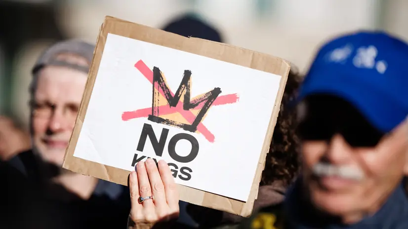 epa12462162 A person holds a placard reading 'No kings!' during a rally in front of the Brandenburg Gate in Berlin, Germany, 18 October 2025. The rally, held under the slogan 'No Kings' expressed solidarity with protests against the U.S. government and the policies of President Donald J. Trump. EPA/CLEMENS BILAN