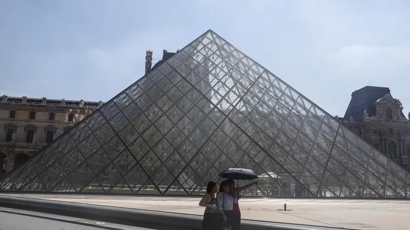 epa12206658 Tourists walk with umbrellas to protect themselves from the sun around the Louvre museum during a hot day in Paris, France, 30 June 2025. From 01 July, Paris and the entire Ile-de-France region, as well as 16 other departments, will be under red alert for extreme heatwave conditions, with temperatures expected to reach 36 to 40 degrees Celsius, with peaks of 41 degrees. This red alert level was last triggered in the Ile-de-France region in August 2020. EPA/TERESA SUAREZ