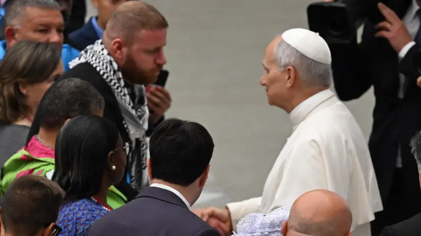 Pope Leo XIV receives a keffiyah during the audience with participants at the Fifth World Meeting of Popular Movements, in the Paul VI Hall, Vatican City, 23 October 2025. ANSA/MAURIZIO BRAMBATTI