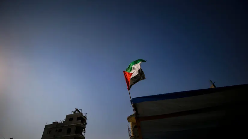 epa12475875 A Palestinian flag is hoisted in the rubble of destroyed buildings in the heavily damaged Sheikh Redwan neighborhood of Gaza City, 23 October 2025. The ceasefire between Israel and Hamas that is currently in place is part of the first phase of a Gaza peace plan that includes a halt in fighting, the release of hostages and prisoners, and the delivery of humanitarian aid. EPA/MOHAMMED SABER