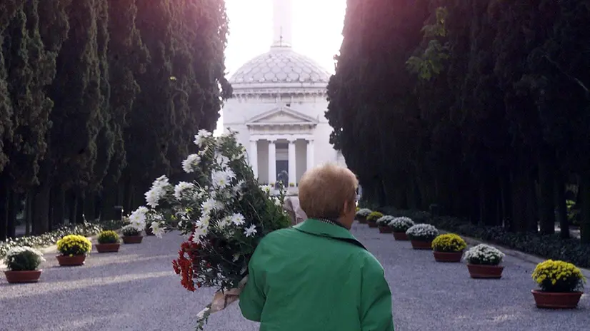 Una signora porta fiori al cimitero Vantiniano - © www.giornaledibrescia.it