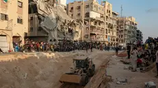 epaselect epa12460750 Locals gather to watch as an excavator works at the site where members of the Al-Qassam Brigades, the military wing of the Hamas movement, are searching for the bodies of Israeli hostages in an area in Hamad City, Khan Younis, in the southern Gaza Strip, 17 October 2025. EPA/HAITHAM IMAD