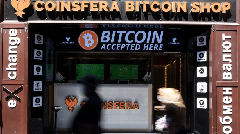 epa09284851 People pass in front of a cryptocurrencies exchange in Istanbul, Turkey, 10 June 2021 (Issued 19 June 2021). Cryptocurrencies trade is too prevalent among young people in Turkey. According to data, there are estimated 5 million active cryptocurrency traders in Turkey. This popularity has also spawned some fraud cases. Owner of Thodex market which have had about 400,000 users of a Turkish crypto exchange, left the country, with users' millions of dollars. However, with the constant depreciation of the Turkish lira, the cryptocurrency market is still very attractive for Turks. Sadik Sahin, owner of a cybercafe in Ankara, had to close his business in March 2020 due to coronavirus restrictions and now uses his computers for mining bitcoins, a cryptocurrency which is very popular in Turkey as an alternative to gold or foreign currencies to protect savings against the strong inflation of the Turkish lira. EPA/ERDEM SAHIN