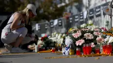 epa12496852 A woman lights a candle in front of the Novi Sad train station ahead of the commemoration in Novi Sad, Serbia, 01 November 2025. The student-led event marks the first anniversary of the railway station canopy collapse that killed 16 people, sparking widespread protests demanding political accountability. EPA/ANDREJ CUKIC