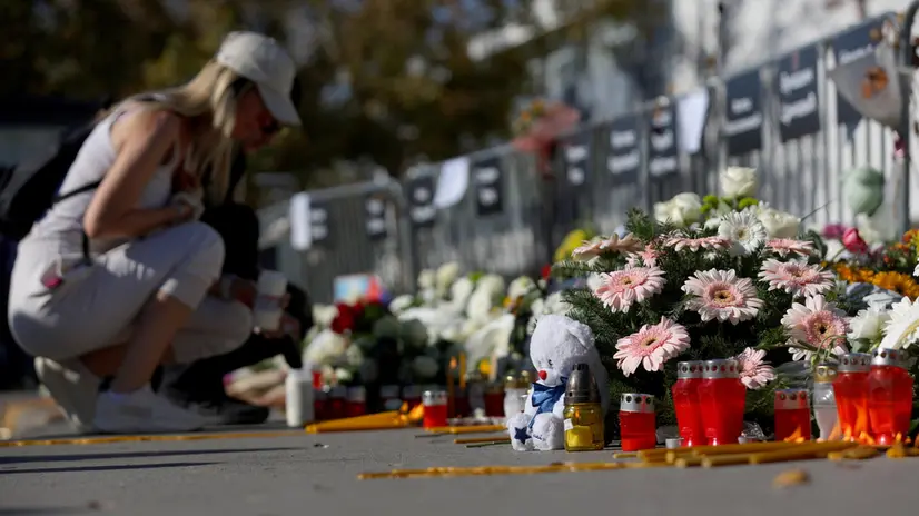 epa12496852 A woman lights a candle in front of the Novi Sad train station ahead of the commemoration in Novi Sad, Serbia, 01 November 2025. The student-led event marks the first anniversary of the railway station canopy collapse that killed 16 people, sparking widespread protests demanding political accountability. EPA/ANDREJ CUKIC