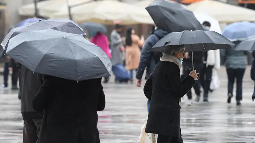 Persone camminano in piazza Duomo sotto una leggera pioggia, Milano, 22 Novembre 2021. Primo assaggio d'inverno con le prime nevicate già da oggi sui comparti alpini intorno ai 1500m di quota. Sono queste le previsioni di Antonio Sanò, direttore e fondatore del sito www.iLMeteo.it. La settimana inizia con tempo molto instabile, tante nubi e piogge sparse su gran parte del Nord, sull'area tirrenica del Centro e pure su molte regioni del Sud e le prime nevicate. ANSA/DANIEL DAL ZENNARO