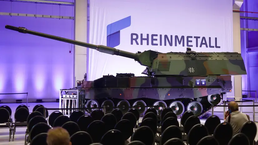 epa12326373 The company logo behind a howitzer 2000 tank during the official opening ceremony of a new Rheinmetall ammunition plant in Unterluess, Germany, 27 August 2025. According to Rheinmetall once fully operational in 2027, the factory will have the capacity to produce up to 350,000 rounds of 155mm artillery ammunition annually. The company also plans to expand production at the plant to include rocket artillery starting in 2026. EPA/HANNIBAL HANSCHKE