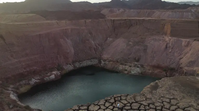 epa11282588 A picture taken with a drone shows people walking on a dry cliff in an abandoned quarry near Timna Park outside the city of Eilat, Israel, 16 April 2024. After the closure of the Timna copper mine in the 1980s, one of the quarries was flooded with groundwater, creating a huge lake. EPA/ABIR SULTAN