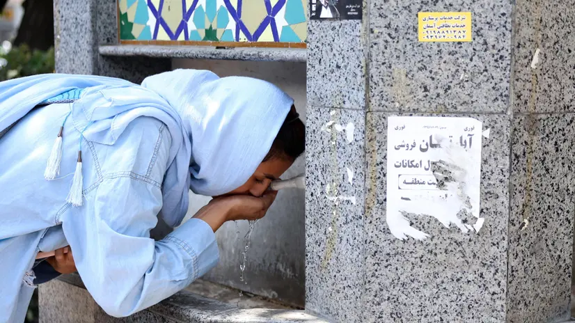 epa11498864 An Iranian woman drinks from a public water fountain during the hot weather in Tehran, Iran, 27 July 2024. The official news agency of the Islamic Republic of Iran IRNA reported that the Iranian government announced tomorrow, 28 July, as a public holiday because of forecasts for a heat wave that is expected to hit Teheran with temperatures of more than 40 degrees Celsius. EPA/ABEDIN TAHERKENAREH