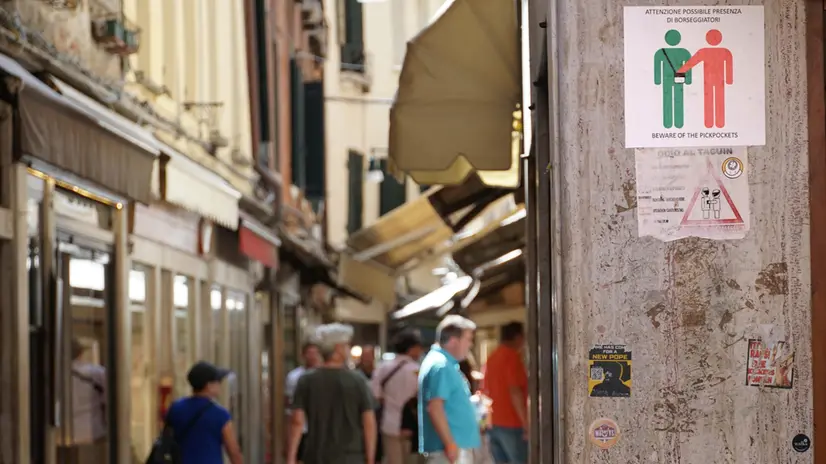 Un avviso di attenzione ai borseggiatori, affisso sul muro in una calle del centro storico vicino piazza San Marco, Venezia 18 luglio 2025. ANSA/ANDREA MEROLA