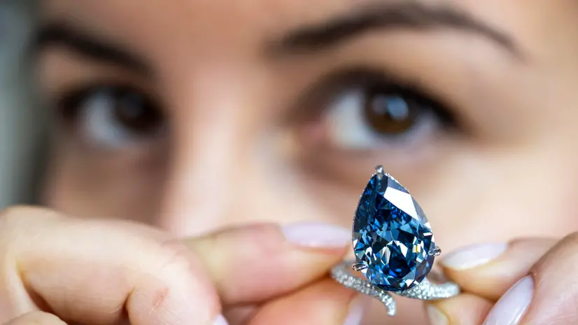epa12510115 A Christie's employee displays the Mellon Blue, a fancy Vivid Blue pear-shaped cut diamond of 9.51 carats, during a preview at the Christie's auction house in Geneva, Switzerland, 07 November 2025. The piece will be auctioned in Geneva on 11 November 2025. EPA/MARTIAL TREZZINI