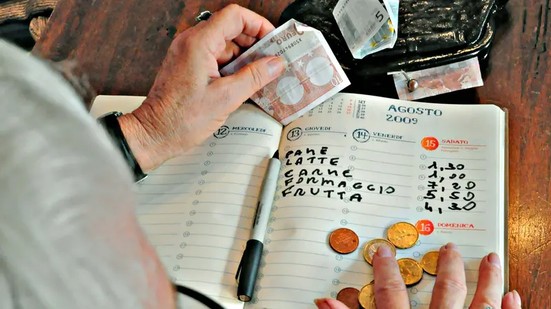Una pensionata mentre fa i conti - © www.giornaledibrescia.it