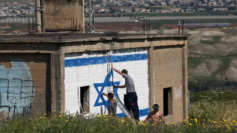 Militanti dipingono la bandiera israeliana su un edificio in Cisgiordania - Foto Ansa © www.giornaledibrescia.it