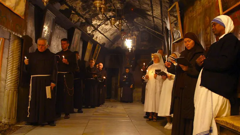 Francescani nella Chiesa della Natività con le candele accese in attesa   dell'arrivo di Gesù