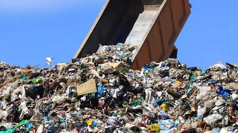 Un mezzo pesante scarica rifiuti in una discarica