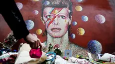 Fiori e candele davanti ad un murale a Brixton, quartiere d’origine dell’artista - Foto Ansa/Epa © www.giornaledibrescia.it