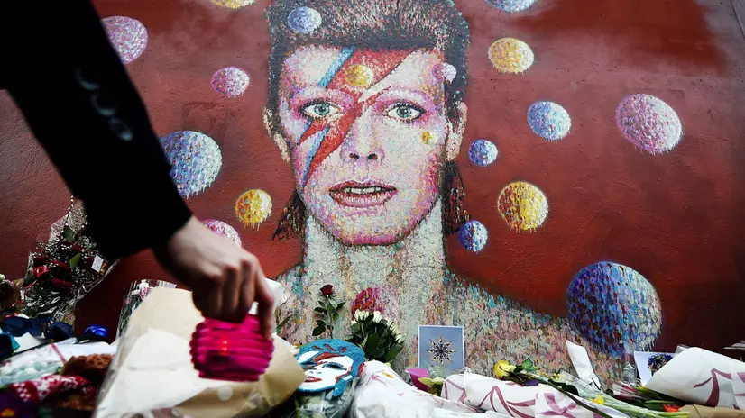 Fiori e candele davanti ad un murale a Brixton, quartiere d’origine dell’artista - Foto Ansa/Epa © www.giornaledibrescia.it