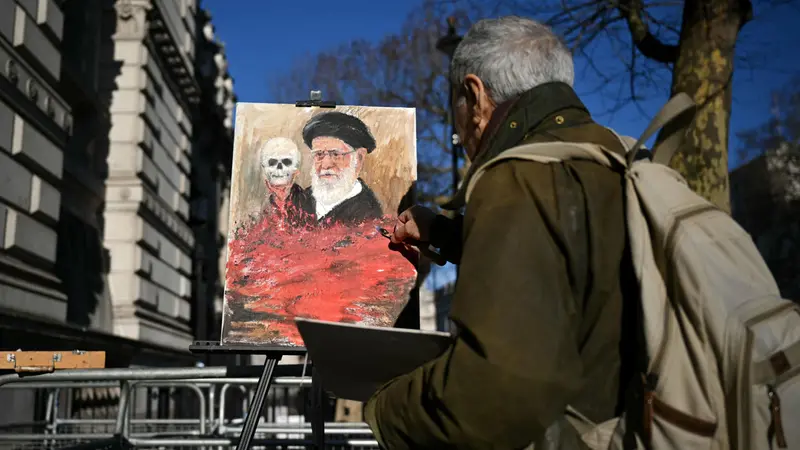 L'artista satirico Kaya Mar dipinge un'opera contro Khamenei fuori da Downing Street - Foto Ansa © www.giornaledibrescia.it