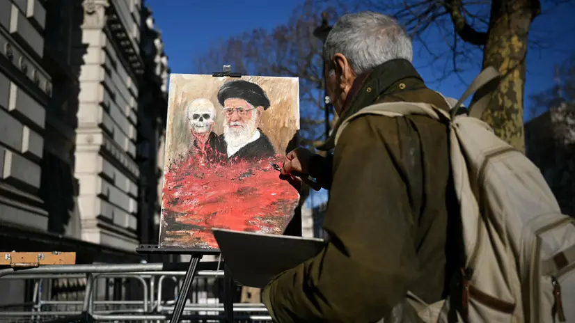 L'artista satirico Kaya Mar dipinge un'opera contro Khamenei fuori da Downing Street - Foto Ansa © www.giornaledibrescia.it