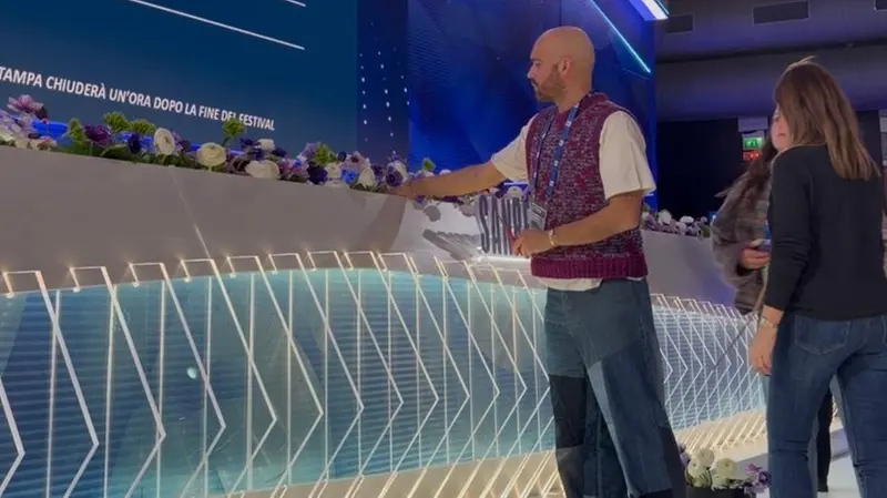 Nicolò Giacomassi sistema i fiori in sala stampa all'Ariston