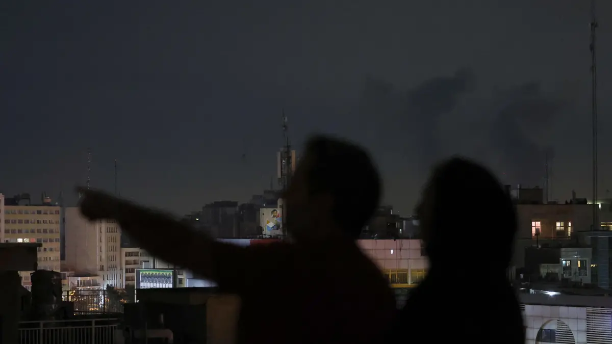 I residenti guardano il fumo dopo gli attacchi aerei su Teheran - Ansa © www.giornaledibrescia.it