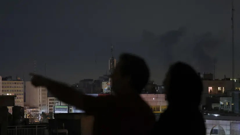 I residenti guardano il fumo dopo gli attacchi aerei su Teheran - Ansa © www.giornaledibrescia.it