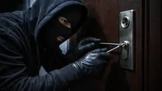 Uno scassinatore cerca di violare la serratura di una porta blindata
