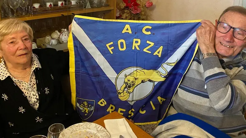Piero accanto alla moglie con l'immancabile bandiera del Brescia - © www.giornaledibrescia.it