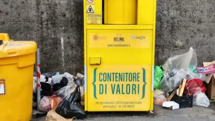 Un classico contenitore giallo circondato dai rifiuti - © www.giornaledibrescia.it