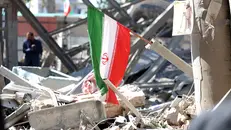 Una bandiera iraniana in mezzo alle macerie (foto d'archivio) - Epa/Abedin Taherkenareh