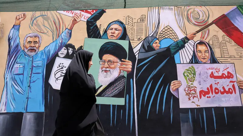 Una donna a Teheran passa davanti a un murale con il volto dell'ex Guida suprema Ali Khamenei - Foto Ansa © www.giornaledibrescia.it