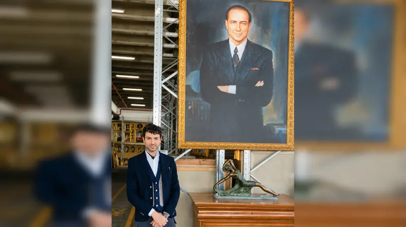 Lucas Vianini davanti a un grande ritratto di Silvio Berlusconi